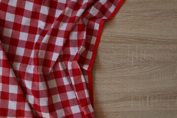 Obraz premium Checkered picnic cloth on wooden table, top view. Space for text