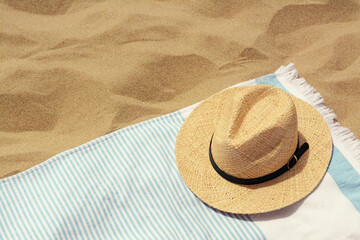 Fototapeta na wymiar Beach towel with straw hat on sand. Space for text
