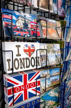 An assortment of tourist postcards themed around Britain and British culture, icons and sights displayed in a retail street stand in central London - a popular travel destination in England.