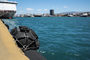 Black floating fender in sea port on sunny day