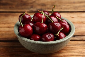 Bowl with ripe sweet cherries on wooden table, closeup