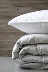 Fototapeta na wymiar Soft folded blanket and pillow on light grey table, closeup