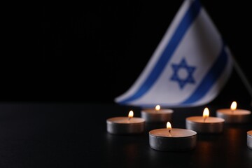 Burning candles on black table, space for text. Holocaust memory day