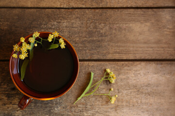 Tasty herbal tea and linden branches on wooden table, flat lay. Space for text