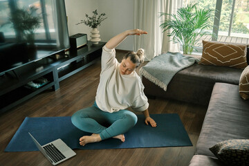 Woman doing online yoga at home. Female trener teaches asana in video conference. Health care, authenticity, sense of balance and calmness.
 - obrazy, fototapety, plakaty