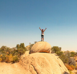 Filipina woman arms up on top of sandstone boulder, Devil's Punchbowl Natural Area, Littlerock,...
