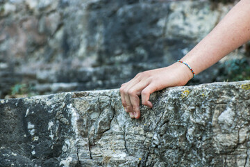 Close up of girl's hand hold the rock while climbing on the rocky terrain