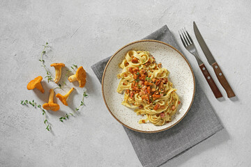 Tagliatelle with chanterelles and bacon, on plate, on white stone background, top view - obrazy, fototapety, plakaty