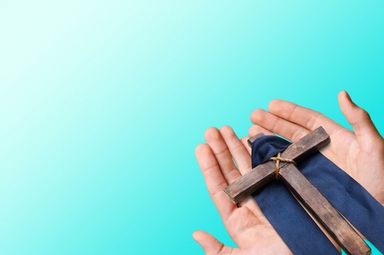 Human hand holding wooden cross crucifix. Catholicism, Christianity, Thanksgiving, Catholic and Christian faith concept.