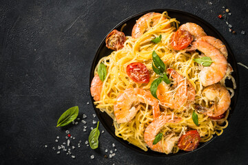 Pasta seafood on black background. Pasta Spaghetti with shrimp, cream sauce and basil. Top view on...