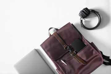 Trendy dark red urban backpack for a laptop with a smartphone and a fountain pen lies on a white...