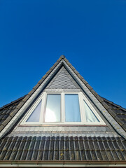 Open roof window in velux style with black roof tiles.