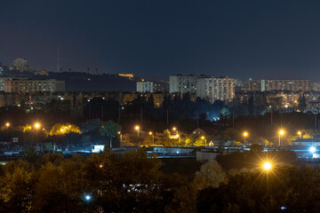 Night cityscape of the big city. Awesome bright, multi colored light at curfew on empty streets. Apartment buildings in bedroom community, commuter town area. Kyiv in last days in july 2022. Ukraine.