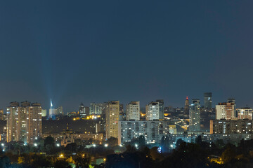 Fototapeta premium Night cityscape of the big city. Awesome bright, multi colored light at curfew on empty streets. Apartment buildings in bedroom community, commuter town area. Kyiv in last days in july 2022. Ukraine.