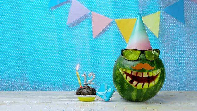 Creative birthday greeting copy space for twelve year old. Video postcard happy birthday muffin with candles with number 12. Watermelon character in a comic smile holiday decorations
