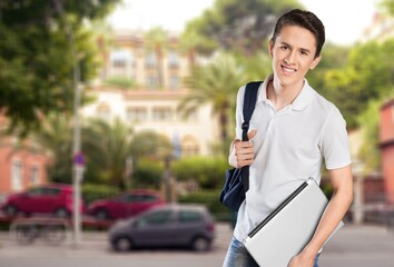 Authentic young handsome man standing on the street. Smiling student in university campus. Education concept