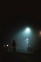 Mujer caminando sola en la noche con niebla