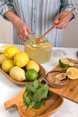 Woman's hands preparing homemade lemonade in glass jug.