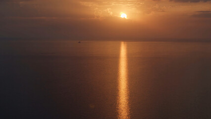 Aerial view of a golden sunset sky background with evening clouds over the sea. Shot. Stunning sky clouds in the sunset with a bright sun path on the sea surface.