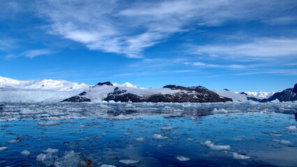 Small bits of ice floating in the bay in front of snow covered mountains at Cierva Cove, Antarctica