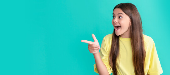 amazed teen girl with long hair point finger on blue background with copy space, wow. Child face, horizontal poster, teenager girl isolated portrait, banner with copy space.