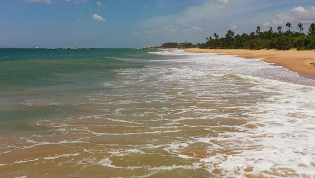 Wide sandy beach with ocean surf and waves. Lankavatara, Sri Lanka.