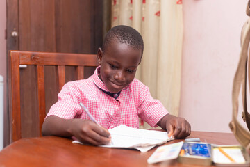 a young black African student child focus holding and writing on paper