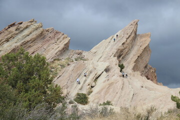 Fototapeta premium Hikers on the surface of tilted white sandstone rocks, Vasquez Rocks Natural Area and Nature Center
