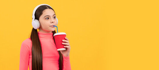 serious child listen music in headphones drink from paper cup on yellow background, coffee. Horizontal poster of isolated child face, banner header, copy space.