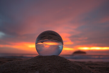 .view of beautiful nature at sunset inside crystal ball..stunning sunset over sea in a crystal ball on the beach. .A image for a unique and creative travel.