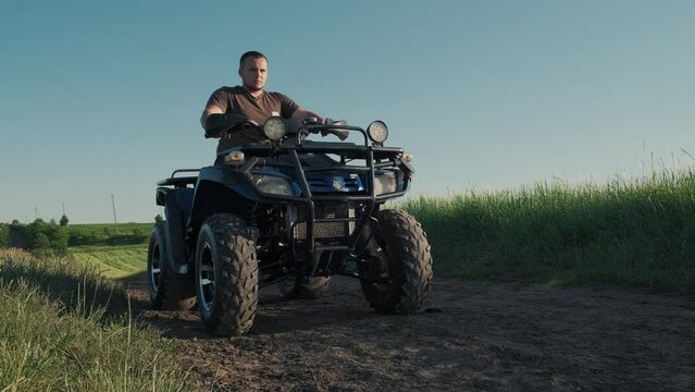Ride on a quad bike, security, dynamics, speed.A guy on a quad motorcycle drifts on wheels.A teenager rides an ATV in a field.Four-wheel ATV transport and extreme sport.little fun.