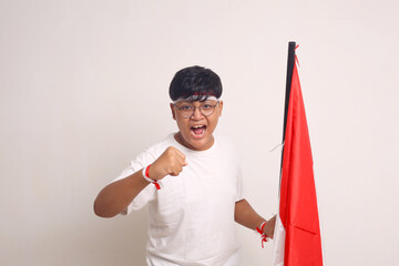 Asian boy holding indonesian flag while clenching his hand. Independence day concept