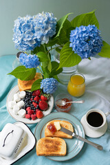 Cute breakfast with fruits and coffee in the garden, blue hydrangea flowers.
