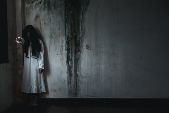 Scary ghost woman. Asian ghost or zombie horror creepy scary have hair covering face and eye reach arm out at abandoned house dark room, female makeup terror zombie face, Happy Halloween day concept