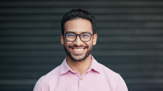 Happy, confident and relaxed young nerd man wearing glasses and smiling while looking into the camera. Portrait of laughing, proud and satisfied IT technician standing in front of office garage door