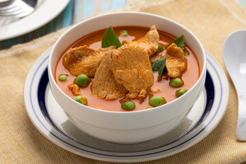 Thai red curry chicken with pea eggplants served in a white serving bowl. Red curry or kaeng phed is one of Thailand’s signature dishes popularly served in Thai restaurants.