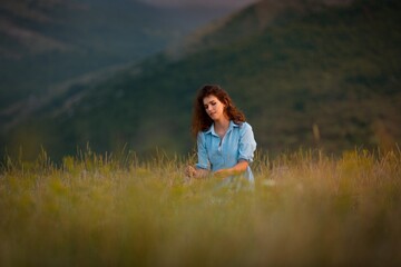 Woman in the field with flowers on landscape background