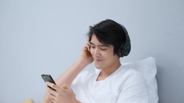 Holiday concept of 4k Resolution. Asian man listening to music in bedroom. Holiday entertainment activities.