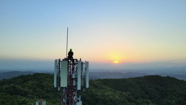 Aerial view passing a Engineer doing maintenance on Radio towers in the mountains