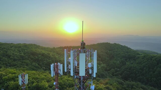 Technician working on the top of a Telecom tower, sunset in the mountains - Orbit, Aerial