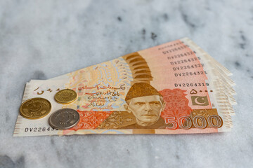 New banknotes of Pakistan 5000 rupees with coins with selective focus