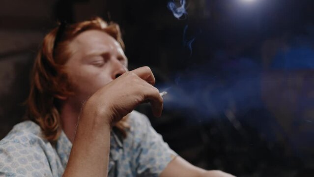 Cinematic shot of mechanic flaking off cigarette sitting on a go-kart.