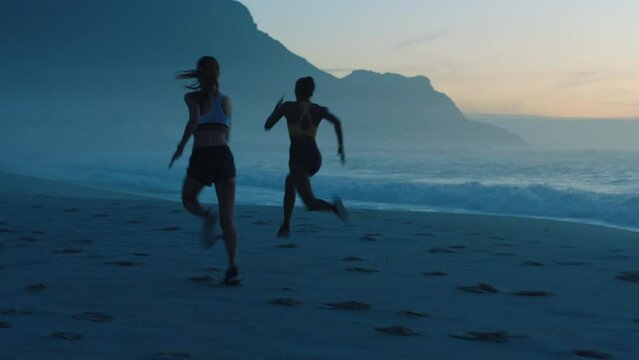 Fit, active and athletic women running, racing and competing on beach workout at sunrise. Sporty and powerful athletes by the sea at sunset running for cardio exercise, health training and stamina