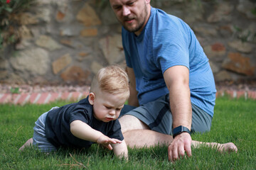 Naklejka na ściany i meble father and baby son playing together outside on green grass