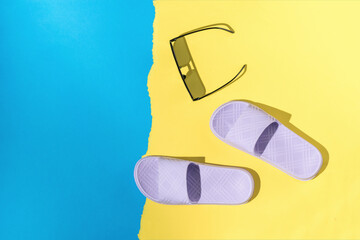 Sunglasses and purple flip-flops on a yellow-blue background.