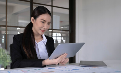 Young asian businesswoman works on tablet with laptop at the office.