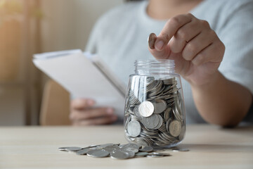 Woman with bills and savings coin jar to pay monthly. Bill payment or inflation concept with saving plan.