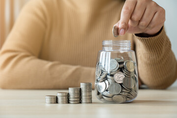 Woman put coin in saving jar and coins stack growing. Savings concept benefit growing in progress.