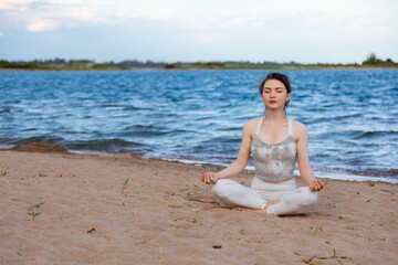 Fototapeta na wymiar Woman practicing yoga outside in lotus pose on beach