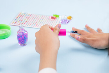 closeup of the hands of a young woman painting her nails at home, with products on the table